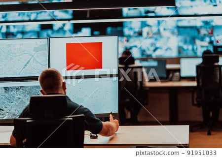 Male security operator working in a data system control room offices Technical Operator Working at workstation with multiple displays, security guard working on multiple monitors Male computer opera Male security operator working in a data system control room offices Technical Operator Working at workstation with multiple displays, security guard working on multiple monitors Male computer opera 91951033