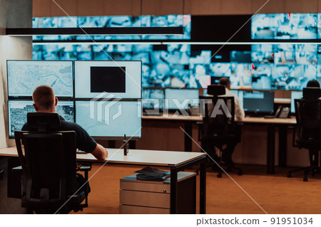 Male security operator working in a data system control room offices Technical Operator Working at workstation with multiple displays, security guard working on multiple monitors Male computer opera Male security operator working in a data system control room offices Technical Operator Working at workstation with multiple displays, security guard working on multiple monitors Male computer opera 91951034