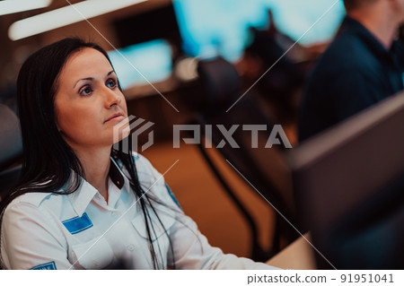 Female security operator working in a data system control room offices Technical Operator Working at workstation with multiple displays, security guard working on multiple monitors 91951041