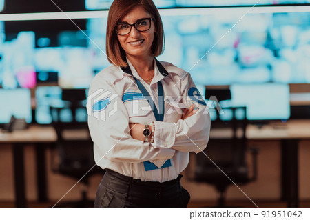 Portrait of female security operator while working in a data system control room offices Technical Operator Working at workstation with multiple displays, security guard working on multiple monitors 91951042