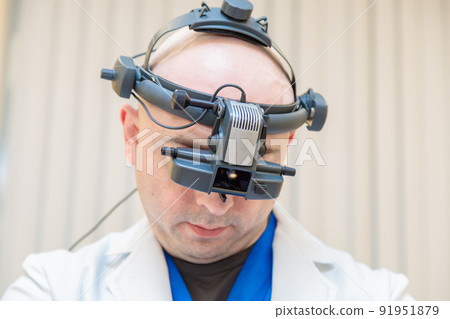 A male ophthalmologist checks a patient's vision with a binocular ophthalmoscope 91951879