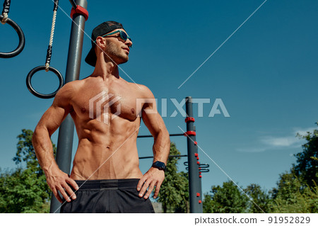 Man thinks about his body and health portrait of a sporty physique. Sports stadium in the Park. Short hair, beard, bare torso. Sunny summer day. Caucasian appearance Man thinks about his body and health portrait of a sporty physique. Sports stadium in the Park. Short hair, beard, bare torso. Sunny summer day. Caucasian appearance 91952829