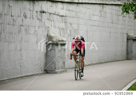 Stylish man walking around the city on bicycles on a weekend, riding on a background of a gray wall. Minimalistic photo of cyclist on a background of a gray wall 91952869