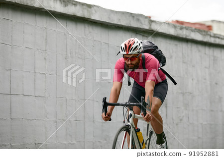 Stylish man walking around the city on bicycles on a weekend, riding on a background of a gray wall. Minimalistic photo of cyclist on a background of a gray wall Stylish man walking around the city on bicycles on a weekend, riding on a background of a gray wall. Minimalistic photo of cyclist on a background of a gray wall 91952881