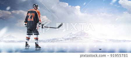 Hockey. Sport concept. Hockey player on ice. Athlete. View from behind. Professional ice hockey player in the mountains. Panorama 91955781