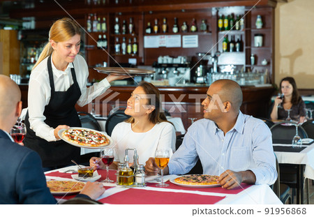 Waitress brought delicious pizza to restaurant guests 91956868