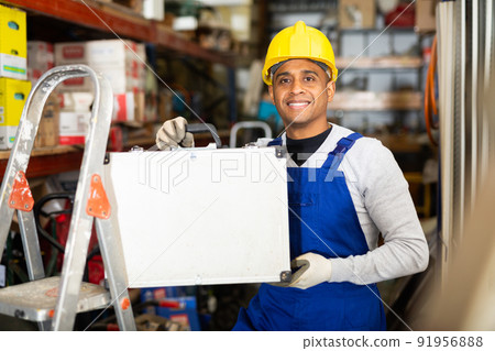 Hispanic craftsman holding case with tools in construction hypermarket Hispanic craftsman holding case with tools in construction hypermarket 91956888