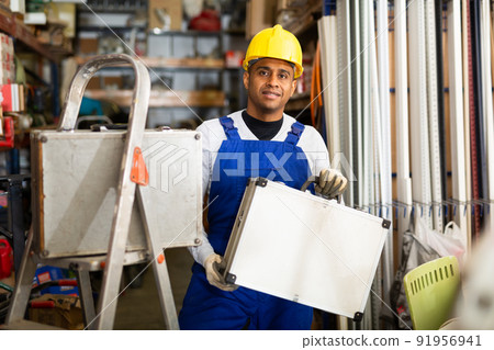 Positive latin american workman with tool suitcase in hardware store Positive latin american workman with tool suitcase in hardware store 91956941