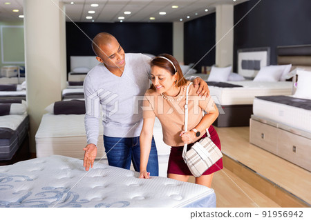 Man and woman choosing mattress in store trying it Man and woman choosing mattress in store trying it 91956942