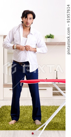 Young man ironing in the bedroom Young man ironing in the bedroom 91957614