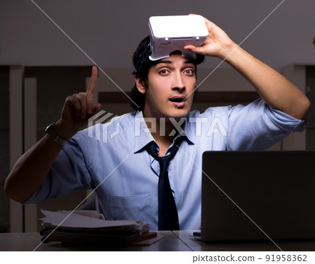 The young employee with virtual glasses at night in the office The young employee with virtual glasses at night in the office 91958362