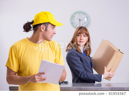 Young male courier delivering box to hotel's reception Young male courier delivering box to hotel's reception 91958367