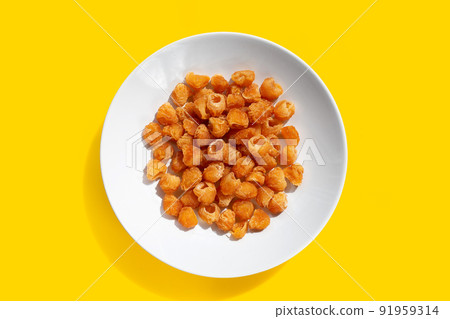 Dried longan in white plate on yellow background. 91959314