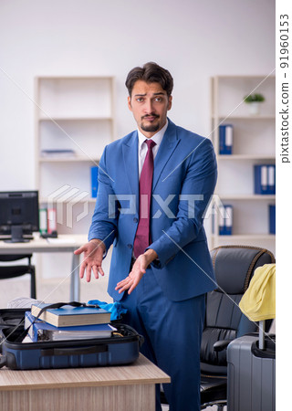 Young male employee preparing for trip at workplace Young male employee preparing for trip at workplace 91960153