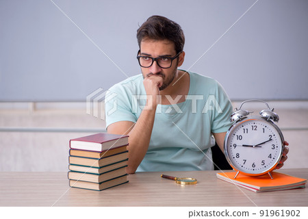 Young male student in time management concept in the classroom 91961902