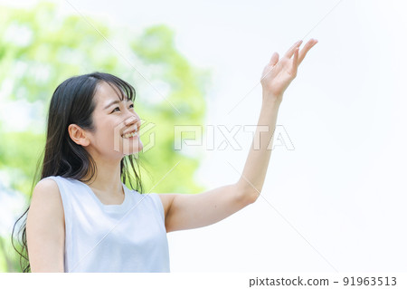 一個日本女人在新鮮的綠色中微笑著握著她的手 一個日本女人在新鮮的綠色中微笑著握著她的手 91963513