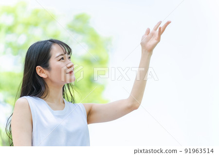 一個日本女人在新鮮的綠色中微笑著握著她的手 一個日本女人在新鮮的綠色中微笑著握著她的手 91963514