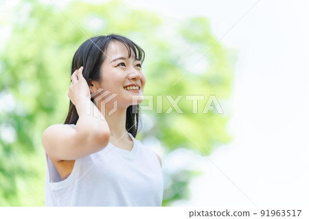 一個微笑的日本女人(洗髮水,美麗的頭髮)用新鮮的綠色撫摸她的頭髮 一個微笑的日本女人(洗髮水,美麗的頭髮)用新鮮的綠色撫摸她的頭髮 91963517