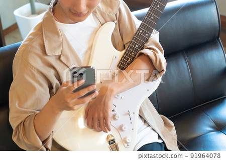 A young man playing a white electric guitar (smartphone) 91964078