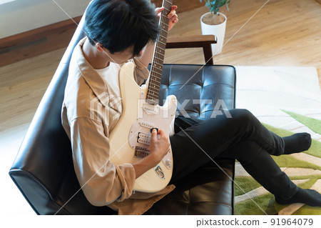 Young man playing white electric guitar 91964079