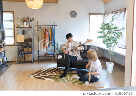 年輕男女在客廳裡彈吉他和貝斯 年輕男女在客廳裡彈吉他和貝斯 91966736