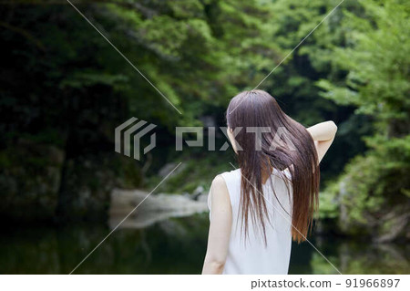 一個女人在鬱鬱蔥蔥的大自然中梳理頭髮 91966897