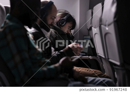 Multiethnic group of passengers flying abroad by airplane jet, using modern devices during international plane transportation. Travelling in economy class with airways flight trip. 91967248