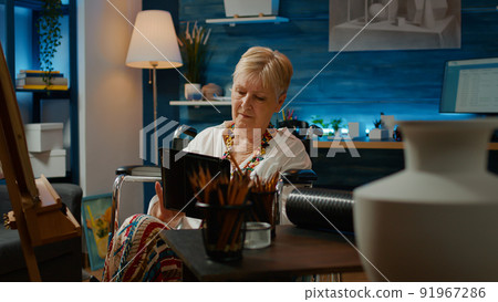 Paralyzed artist with physical disability drawing vase model and using digital tablet to find artwork inspiration. Wheelchair user with health condition creating artistic sketch masterpiece. 91967286