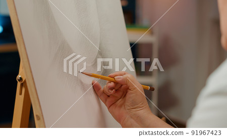 Hand of professional artist drawing vase model design with pencil on white canvas and wooden easel. Using creative skills and artistic tools to create outline sketch with inspiration. Close up. Hand of professional artist drawing vase model design with pencil on white canvas and wooden easel. Using creative skills and artistic tools to create outline sketch with inspiration. Close up. 91967423