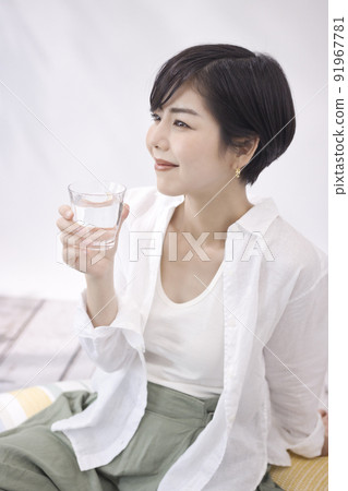 Young woman drinking water in the living room Young woman drinking water in the living room 91967781