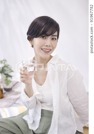 Young woman drinking water in the living room Young woman drinking water in the living room 91967782