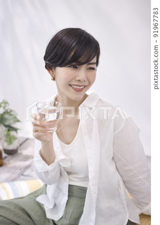 Young woman drinking water in the living room Young woman drinking water in the living room 91967783
