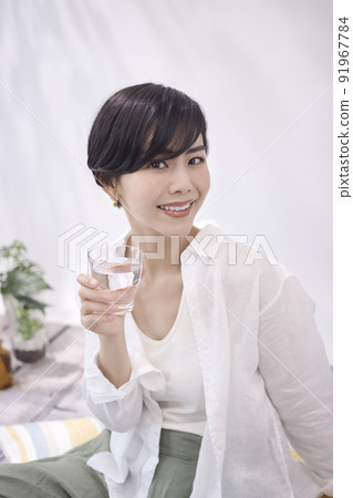 Young woman drinking water in the living room Young woman drinking water in the living room 91967784