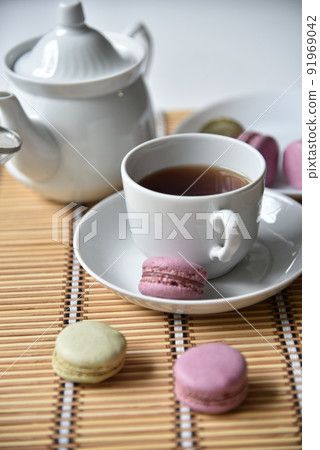 Porcelain teapot with a cup of tea and macaroons 91969042