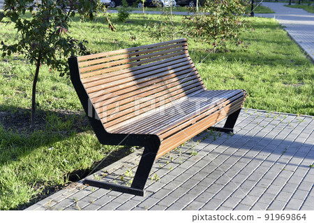 A large wooden bench in the city park in summer A large wooden bench in the city park in summer 91969864