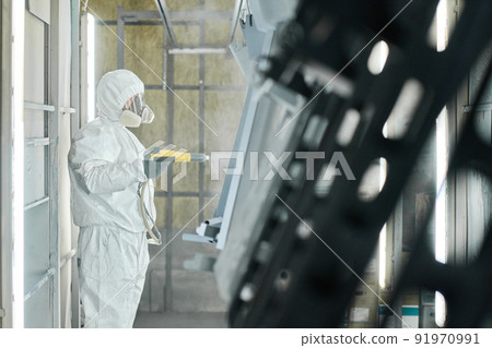 Industrial worker in protective workwear using spray gun to paint metal details at factory Industrial worker in protective workwear using spray gun to paint metal details at factory 91970991