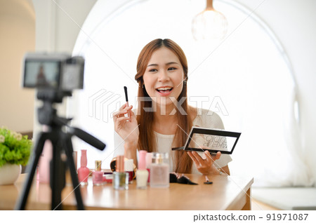Attractive young Asian female beauty blogger giving advice, making a makeup tutorial video. Attractive young Asian female beauty blogger giving advice, making a makeup tutorial video. 91971087