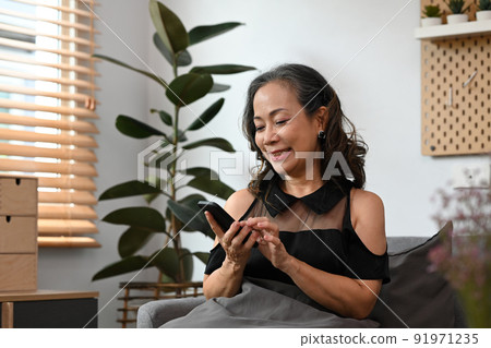 Happy middle aged lady shopping or chatting online in social network on smart phone Happy middle aged lady shopping or chatting online in social network on smart phone 91971235