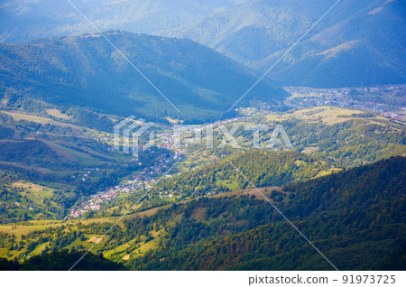 mountain landscape on a sunny autumn morning. village in the distant valley. view from the top of a forested hill mountain landscape on a sunny autumn morning. village in the distant valley. view from the top of a forested hill 91973725