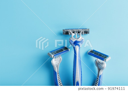 Blue shaving machines in a row on a blue background with ice cubes Blue shaving machines in a row on a blue background with ice cubes 91974111