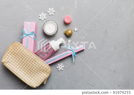 Christmas flat lay with makeup cosmetic products in cosmetic bag on colored background. Top view New year Beauty concept 91974255