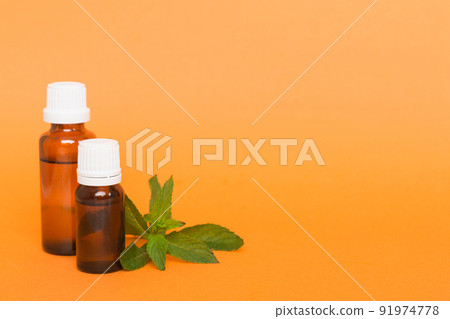 Natural Mint Essential Oil in a Glass Bottle. organic cosmetics with herbal extracts of mint on colored background 91974778