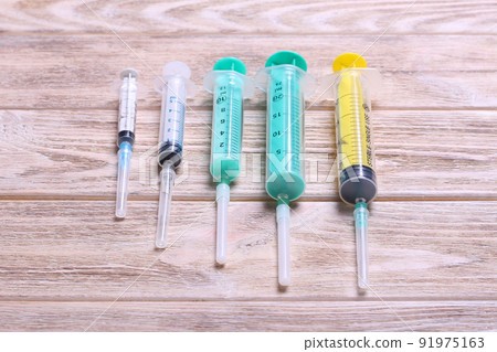 Top view of many syringes prepared for injection at wooden background. Treatment concept with copy space Top view of many syringes prepared for injection at wooden background. Treatment concept with copy space 91975163