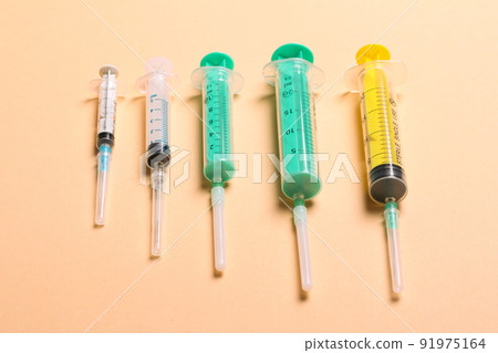 Top view of medical syringes with needles at orange background with copy space. Injection treatment concept Top view of medical syringes with needles at orange background with copy space. Injection treatment concept 91975164