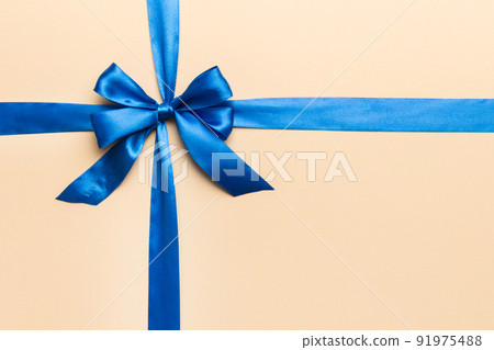 Top view of blue ribbon rolled and blue bow isolated on colored background. Flat lay with copy space Top view of blue ribbon rolled and blue bow isolated on colored background. Flat lay with copy space 91975488