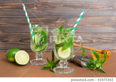 Mojito cocktail. Refreshing mojito cocktail with lime, lemon and mint in a tall glass with a stick Mojito cocktail. Refreshing mojito cocktail with lime, lemon and mint in a tall glass with a stick 91975563