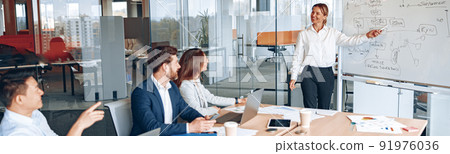 Skilled mature caucasian leader coaching interested business people, giving presentation in office Skilled mature caucasian leader coaching interested business people, giving presentation in office 91976036