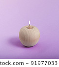 A wooden apple like a burning candle on a purple background. 91977033