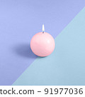 A pink round candle on a blue and purple background. 91977036