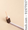 Ice cream on a stick like a brush leaves a mark on the orange background. 91977037